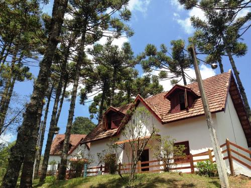a white house with a fence and some trees at Hotel Fazenda Golden Park Campos do Jordão in Campos do Jordão