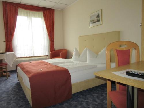 ein Hotelzimmer mit einem Bett, einem Schreibtisch und einem Tisch in der Unterkunft Hotel Lindenhof in Königstein an der Elbe