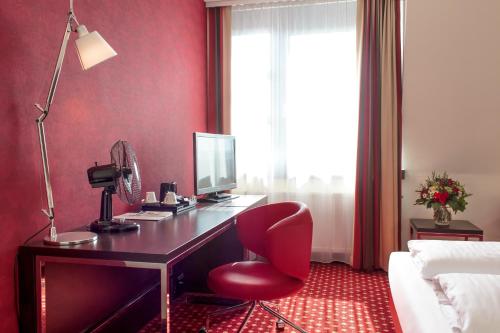 a desk with a computer and a red chair in a room at Best Western Plaza Hotel Wels in Wels