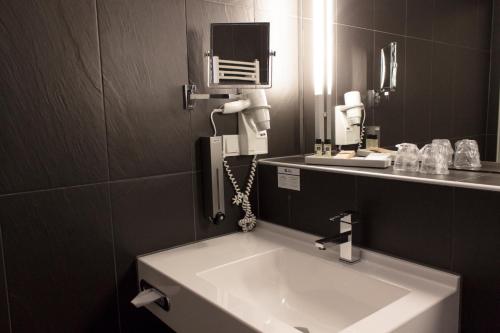 a bathroom with a white sink and a phone at Best Western Plaza Hotel Wels in Wels