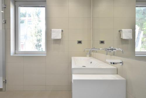 a white bathroom with a sink and a window at Chiponsky One - 5 star beachfront property in Bol