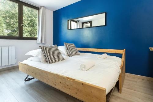 een slaapkamer met een bed met een blauwe muur bij Apartment Jonquille Terrasse in Chamonix-Mont-Blanc