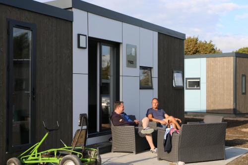 two men sitting on chairs outside of a tiny house at Stadscamping Zeeland in Middelburg