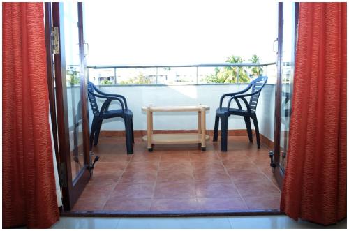 a patio with two chairs and a table on a balcony at Pondicherry Executive Inn in Puducherry