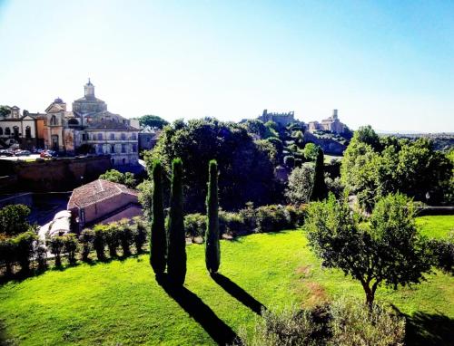 a green field with cypress trees and a city at Tuscania Terme Suites Apartments in Tuscania