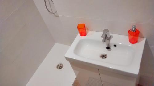 拉薩特的住宿－Apartamento Juan XXIII Plaza，白色浴室内的白色水槽,配有橙色杯子