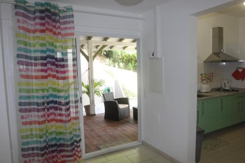 a kitchen with a sliding glass door with a colorful curtain at Plaisir de vivre - T2 Proche CHUM La Meynard in Fort-de-France