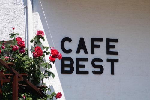 ein Café bestes Schild an der Wand mit roten Blumen in der Unterkunft Cafe Best  Ferienwohnung in Bullau