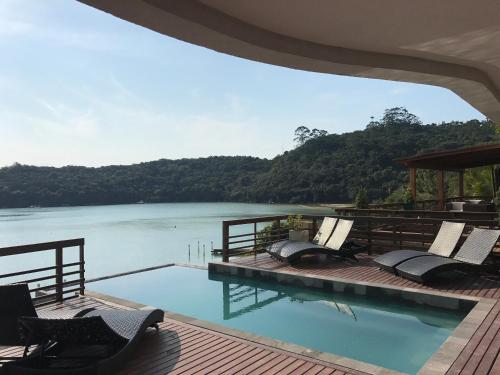 a swimming pool with chairs and a view of a river at Caixa D'aço Exclusive Hotel in Porto Belo