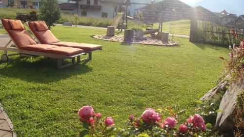 a bench in a yard with a playground and pink roses at Haus Moosalm in Berwang