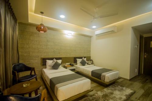 Habitación de hotel con 2 camas y mesa en Hotel Grand Elegance en Ahmedabad