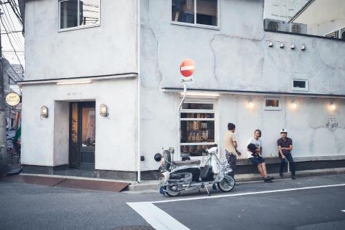 a group of people standing outside of a building with a scooter at 36hostel in Hiroshima