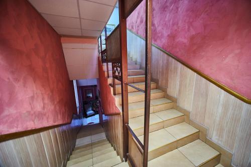 a winding staircase in a house with pink walls at Hotel Izvora in Ruse