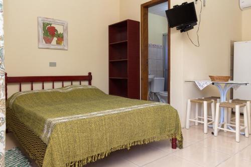1 dormitorio con 1 cama, TV y baño en Residencial Brown, en Bombinhas