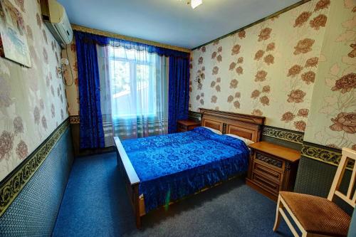 a bedroom with a blue bed and a window at Hotel Izvora in Ruse