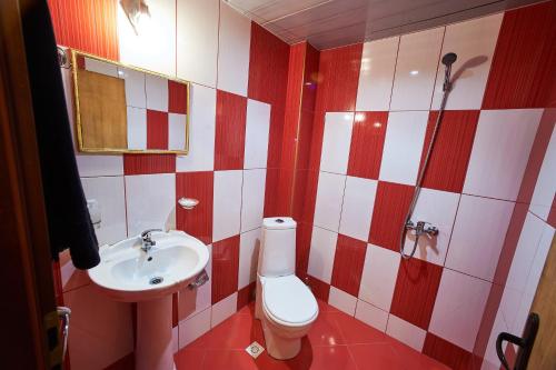 a red and white bathroom with a toilet and a sink at Hotel Izvora in Ruse