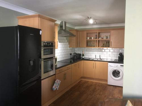 a kitchen with wooden cabinets and a black refrigerator at 1 St Ellas House Apartment in Eyemouth