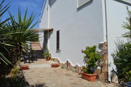a white house with potted plants in a courtyard at B&B Gianni e Pia in Luogosanto