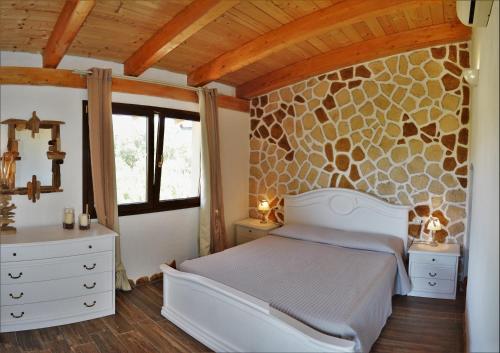een slaapkamer met een bed en een stenen muur bij B&B Gianni e Pia in Luogosanto
