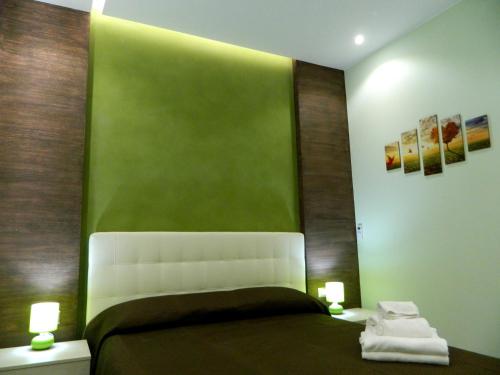 a bedroom with a bed with a green wall at Il Borghese Tourist House in Gela
