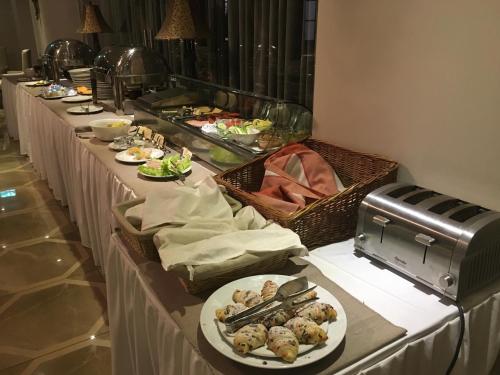 a row of buffet tables with plates of food at Hotel Capitulum in Győr