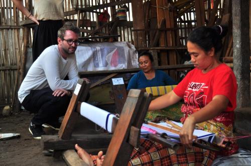 a group of people sitting around a table with books at Mu Homestay in Tetebatu