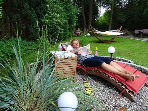 a woman laying in a hammock in a garden at Gästehaus Schwentineblick in Malente