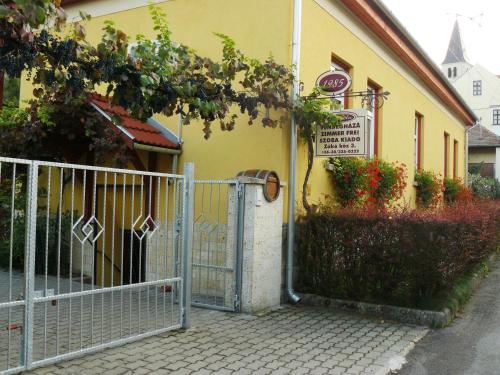 um edifício amarelo com um portão em frente em Angéla Vendegház em Tokaj