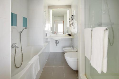 a white bathroom with a toilet and a sink at Hotel Puerta de Bilbao in Barakaldo