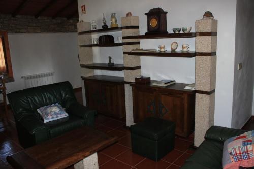 a living room with a couch and a clock on the wall at Chou da Covinha in Arrimal