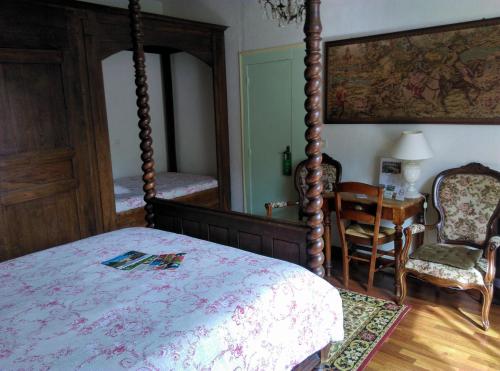 ein Schlafzimmer mit einem Himmelbett, einem Tisch und einem Stuhl in der Unterkunft Le Val du Roy in Joinville