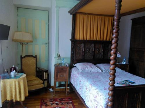 a bedroom with a canopy bed and a table and a chair at Le Val du Roy in Joinville