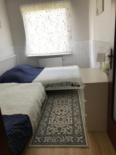 a bedroom with two beds and a window and a rug at Apartament KORAB Władysławowo-Cetniewo in Władysławowo