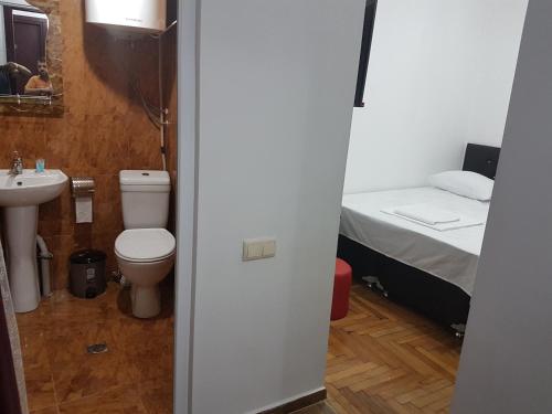 a bathroom with a toilet and a sink and a bed at Pheria in Batumi