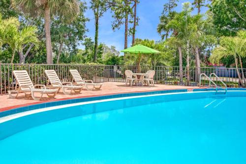 a swimming pool with chairs and an umbrella at Days Inn by Wyndham Bradenton - Near the Gulf in Bradenton