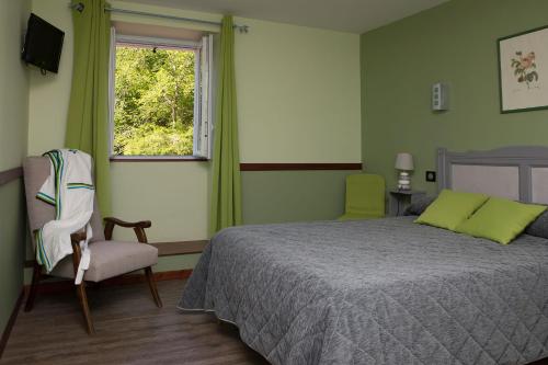 a bedroom with a bed and a chair and a window at Les Sources de La Nive in Esterençuby