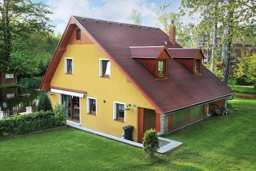 a yellow house with a brown roof on a yard at Chalupa U rybníčku in Krásná Lípa