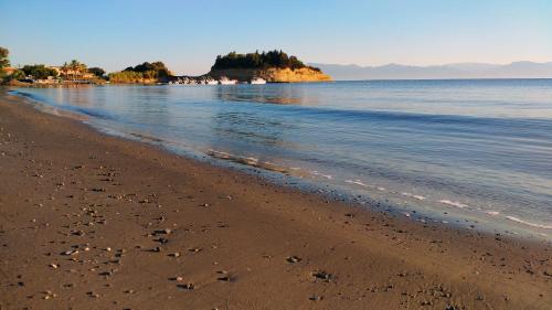 a beach with footprints in the sand and the water at Panorama Sidari in Sidari