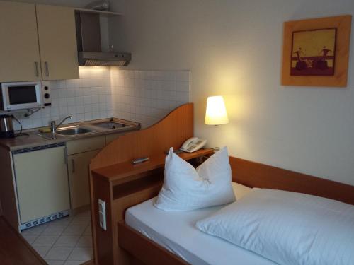 ein Hotelzimmer mit einem Bett mit Telefon darauf in der Unterkunft Hotel am Exerzierplatz in Mannheim