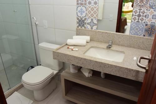 a bathroom with a toilet and a sink and a mirror at Pousada Solar Dos Carneiros in Praia dos Carneiros