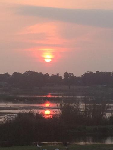 a sunset over a body of water with trees at Bottom of Boden in Benoni