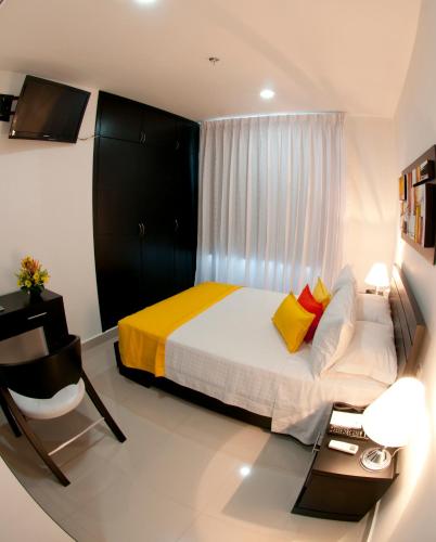 a small bedroom with a bed and a television at Hotel Atlantic Lux in Cartagena de Indias
