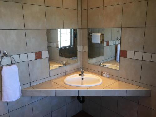 a bathroom with a sink and two mirrors at Bottom of Boden in Benoni