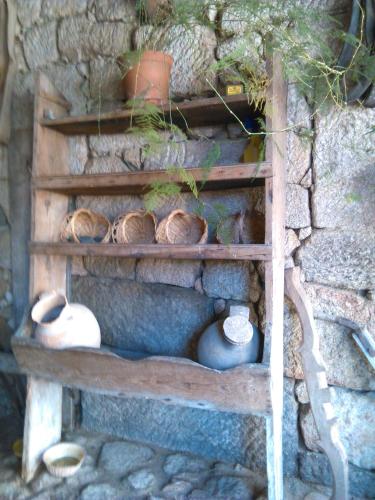 a shelf with pots and vases on a stone wall at Casa das Freiras in Marialva