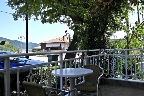 a table and chairs on a balcony with a tree at Roula Rooms in Stratoni