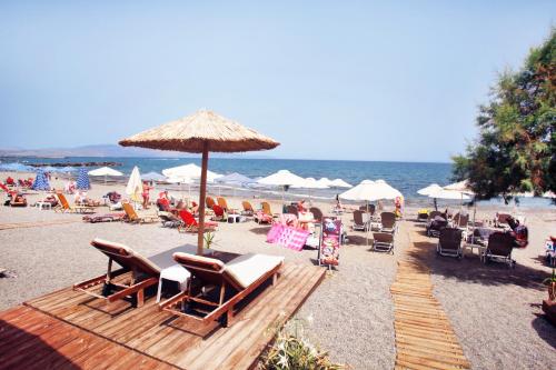 a beach with a lot of chairs and an umbrella at Studios Vasilis in Agia Marina Nea Kydonias