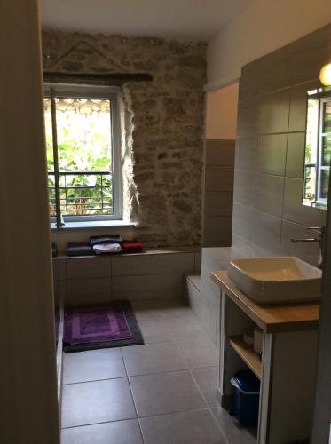 baño con lavabo, bañera y ventana en Maison Ancienne Minervois, en La Caunette