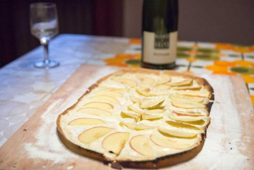 a pizza sitting on a table next to a bottle of wine at Maison d'hôtes Aux Deux Cigognes in Gries