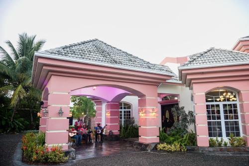 a pink house with people sitting at tables in front of it at Villa Dora Mae in Ocho Rios