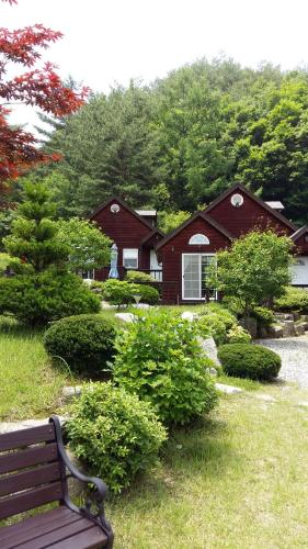 a bench in front of a house with trees at Sisilli Pension in Pyeongchang 